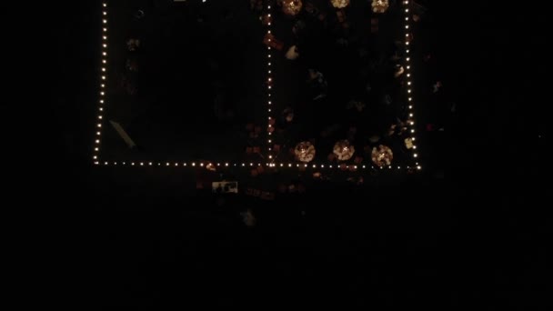 Вид сверху на открытую площадку с подсветкой и столиками со свечами на свадьбе с гостями и молодоженами — стоковое видео