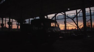 Gün batımında açık bir depo ya da metal yapıları olan bir fabrika atölyesinde kamyonet.