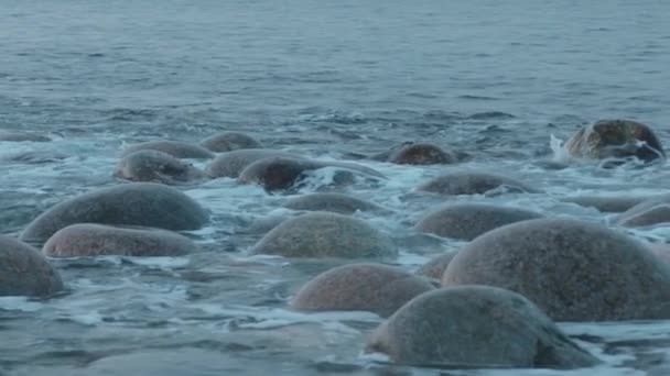 Ondas do mar quebrar em enormes pedras redondas e despeje sobre eles. Movimento lento — Vídeo de Stock