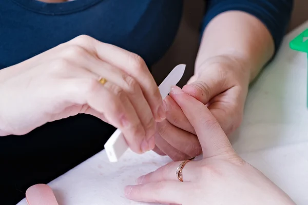 Closeup of a manicurist filing a female's nails — Stock Photo, Image