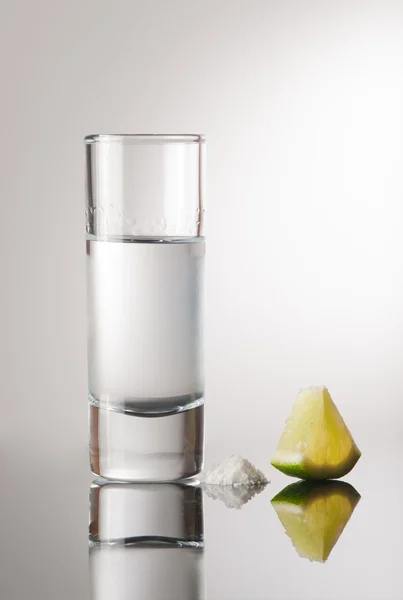Tequila in un bicchiere con una fetta di limone — Foto Stock