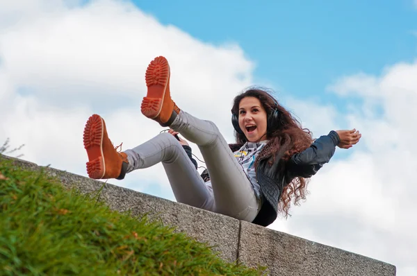 Menina está feliz sentado em seus fones de ouvido — Fotografia de Stock