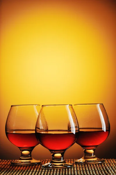 Trzy szklanki koniaku na żółtym tle — Zdjęcie stockowe