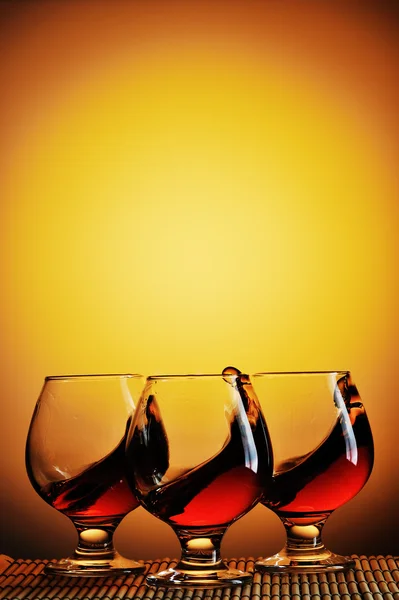 Three glasses of cognac on yellow background — Stock Photo, Image