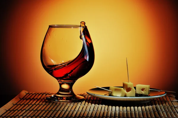 Glass of cognac with cheese plate — Stock Photo, Image