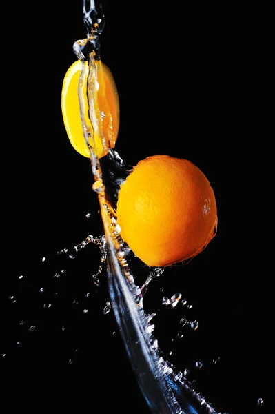 Laranja com respingo de água em um fundo preto — Fotografia de Stock