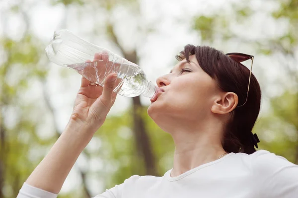Frau trinkt Wasser aus Flasche Stockbild