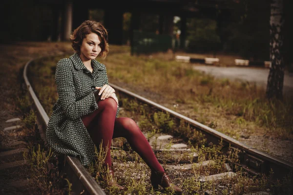 Young girl is seating on the rail — Stock Photo, Image