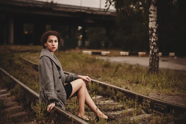Ung flicka sittplatser på järnväg — Stockfoto