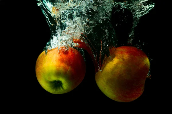Gula äpplen med stänk vatten på en svart bakgrund — Stockfoto