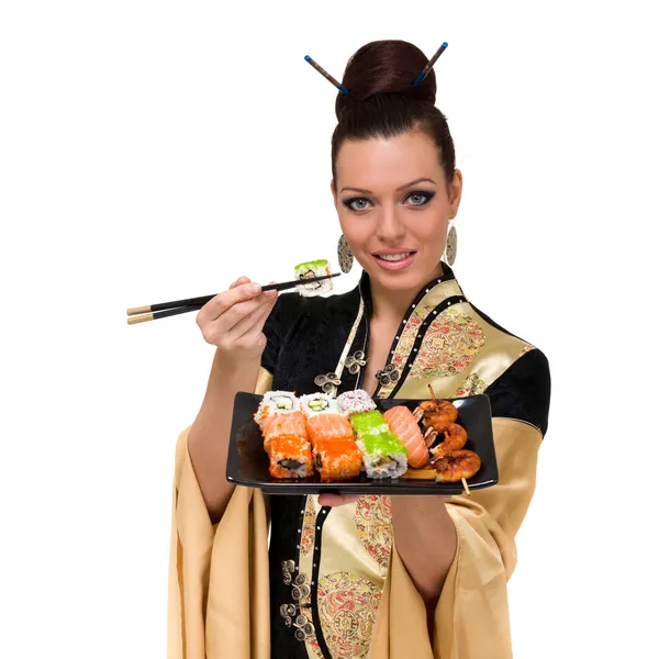 Frau in traditioneller Kleidung isst Sushi Stockbild