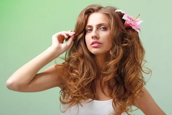 Woman with flower against green background — Stock Photo, Image