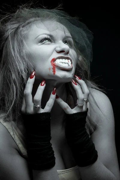 Жінка вампір з іклами на чорному тлі — стокове фото