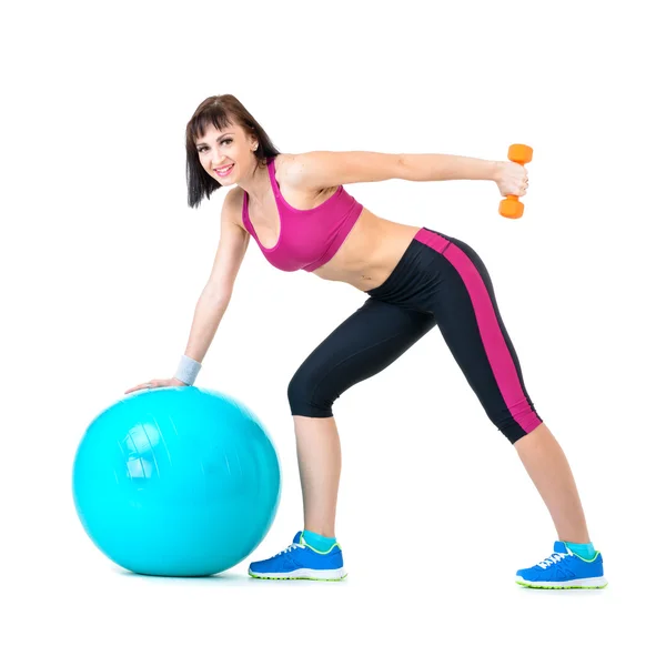 Mujer joven haciendo ejercicio con pesas en una pelota de fitness —  Fotos de Stock