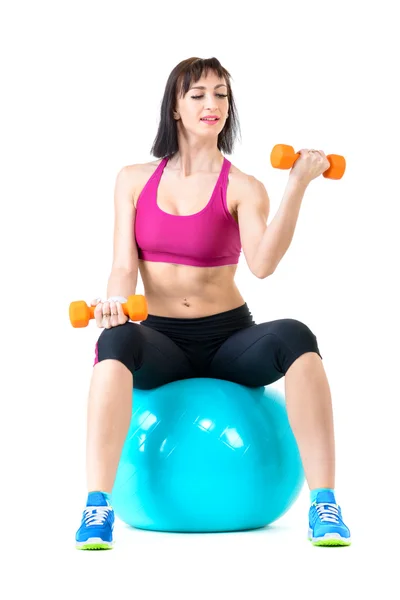 Mujer joven haciendo ejercicio con pesas en una pelota de fitness —  Fotos de Stock