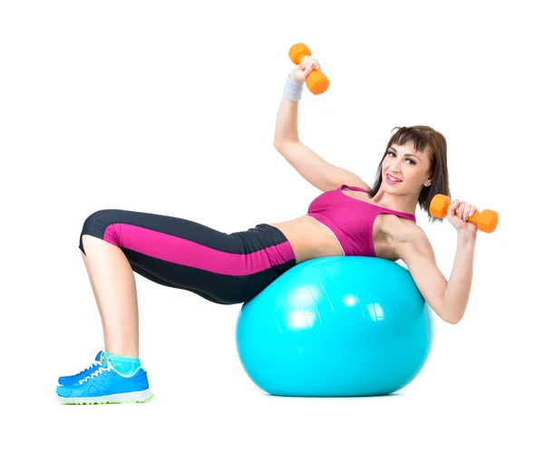 Mladá žena cvičení s činkami na fitness míče — Stock fotografie