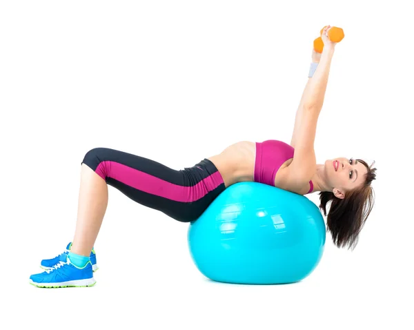 Mujer joven haciendo ejercicio con mancuernas colocadas en una pelota de fitness — Foto de Stock