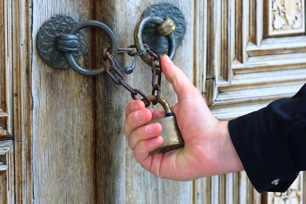 Hand met oude ijzer veiligheidsslot sierdoeleinden houten deur — Stockfoto