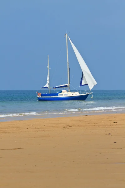 Blauwe jacht verankerd in de buurt van zandstrand — Stockfoto