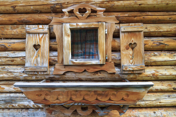 Window with heart shutters of a wooden log cabin in the European