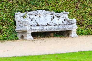 Ornamental English garden with stone bench clipart