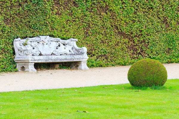 Jardín inglés ornamental con banco de piedra — Foto de Stock