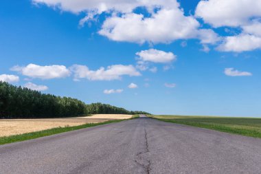 Tarlada Paved yolu ve mavi gökyüzünde bulutlar.