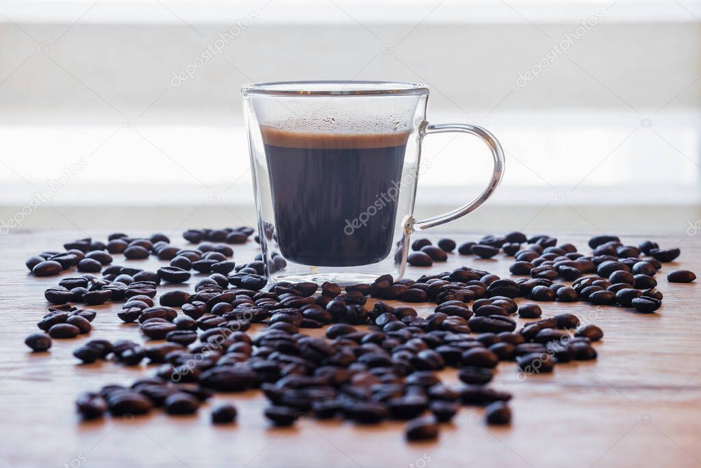 Black coffee in a glass cup on a wooden table.