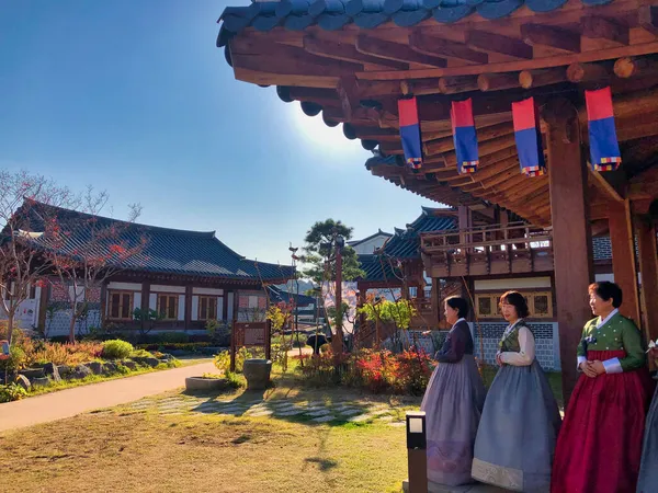 Geleneksel Koreli kadınlar eski bir tapınakta yeşil çimenler ve mavi gökyüzü ile Seul 'ün yanındaki yerel tatil partisinde giyiniyorlar.