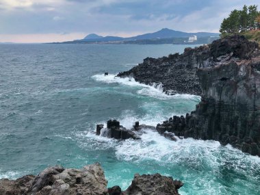 Kara volkanik kayalar ve dalgaların vurduğu engebeli deniz manzarası, yukarıdan manzara, Güney Kore 'de güzel manzara.