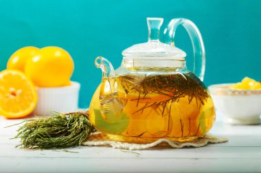 Borosilikat bardaktan yapılmış şeffaf cam çaydanlık mavi arka planda bitkisel çay ve limon. Güzel şeffaf çaydanlık ve bitki çayı.