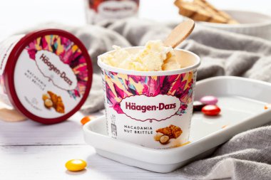 KYIV, UKRAINE - Şubat 06, 2022: HAAGEN-DAZS vanilyalı dondurma bir kova vanilyalı dondurma, ahşap çubuklu karamel aromalı fındık. Yakın plan.