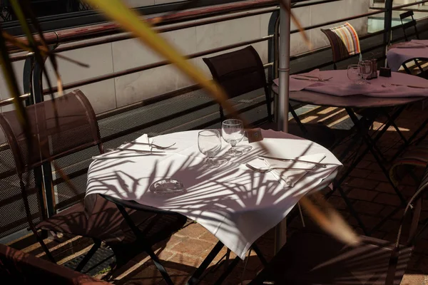 有一张白色桌布的桌子放在一个有棕榈树影子的夏季阳台上 — 图库照片