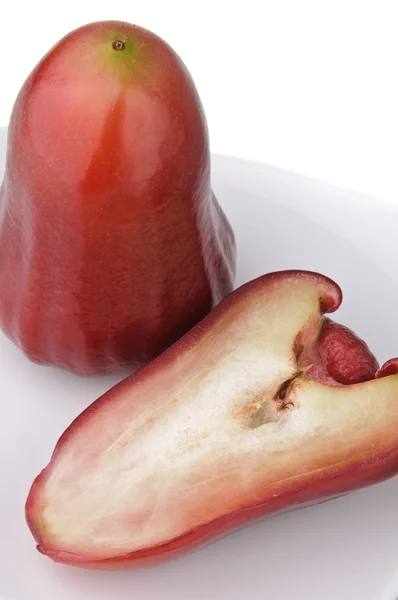 One and a half of red rose apple on white plate — Stock Photo, Image