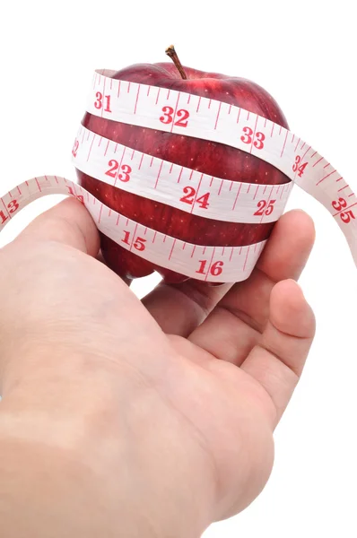 Left hand holding a red apple with measuring tape — Stock Photo, Image