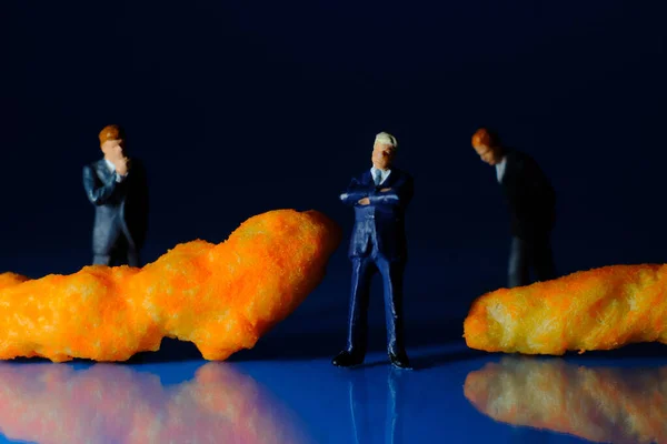 Miniaturowi Biznesmeni Rozważający Ser Puff Niezdrowe Fast Food Snack Makro — Zdjęcie stockowe