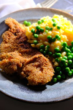 Southern style breaded chicken cutlets with side of mac and cheese with green peas clipart