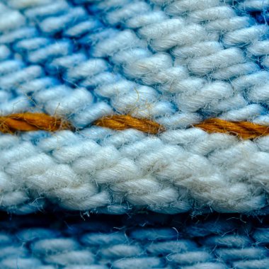 Makro yakın plan kot pantolon. Kenarlarına turuncu ve mavi dikişler.