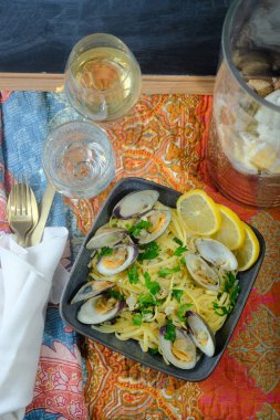 Küçük boyunlu beyaz şarap, midye sosu ve maydanoz garnitürlü linguine.