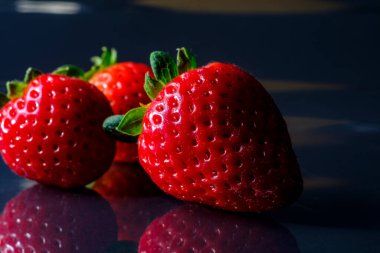 Koyu mavi arka planda taze olgun çilekler.