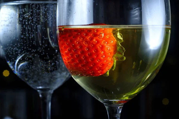 Romantic date at fancy restaurant with pinot grigio white wine with strawberry floating in glass