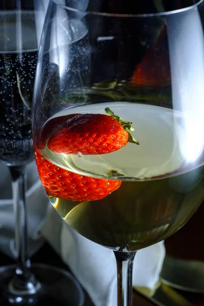 Romantic date at fancy restaurant with pinot grigio white wine with strawberry floating in glass