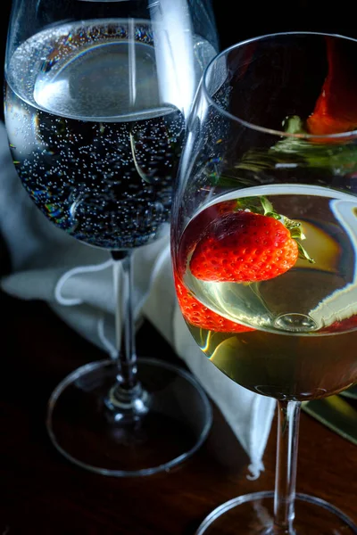 Romantic date at fancy restaurant with pinot grigio white wine with strawberry floating in glass