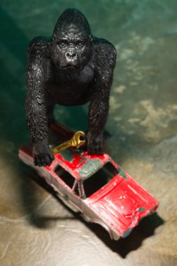 Toy gorilla holding wrench to work on old red car concept