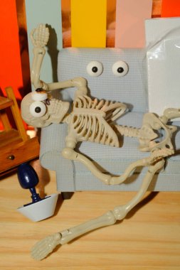 Concept for how overwhelming creativity can be, shown as a crazy skeleton at home on the couch