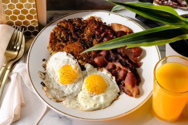 American breakfast two eggs sunny side up with bacon hash browns and a glass of fresh squeezed orange juice