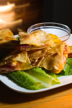 Ham and cheese quesadilla in moody bar setting