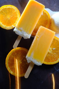 Oranges and cream vanilla ice pops melting on kitchen counter