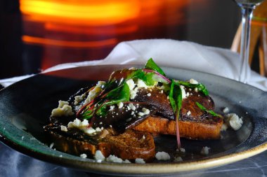 Open faced portobello mushroom sandwich on toast with feta cheese and garnished with sauteed chard