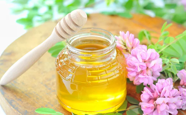 Bal dolu kavanoz ve akasya pembe ve beyaz çiçekler ile sopa